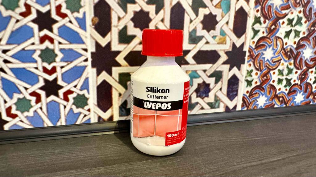 Silikonentferner im Test: Eine Flasche steht vor einer bunten Wand.