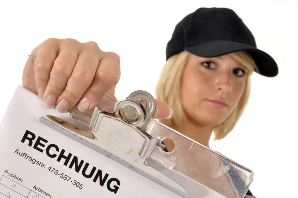 Werkzeugkoffer mit Akkuschrauber im Test: Eine junge Frau in Handwerker-Outfit hält eine Rechnung hoch.