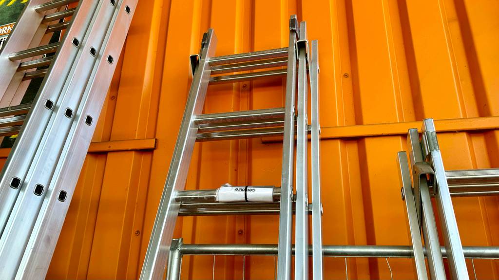 Getestet: Mehrzweckleitern; Nahaufnahme von einem zusammengeschobenen Modell, das an einer orangen Wand lehnt.