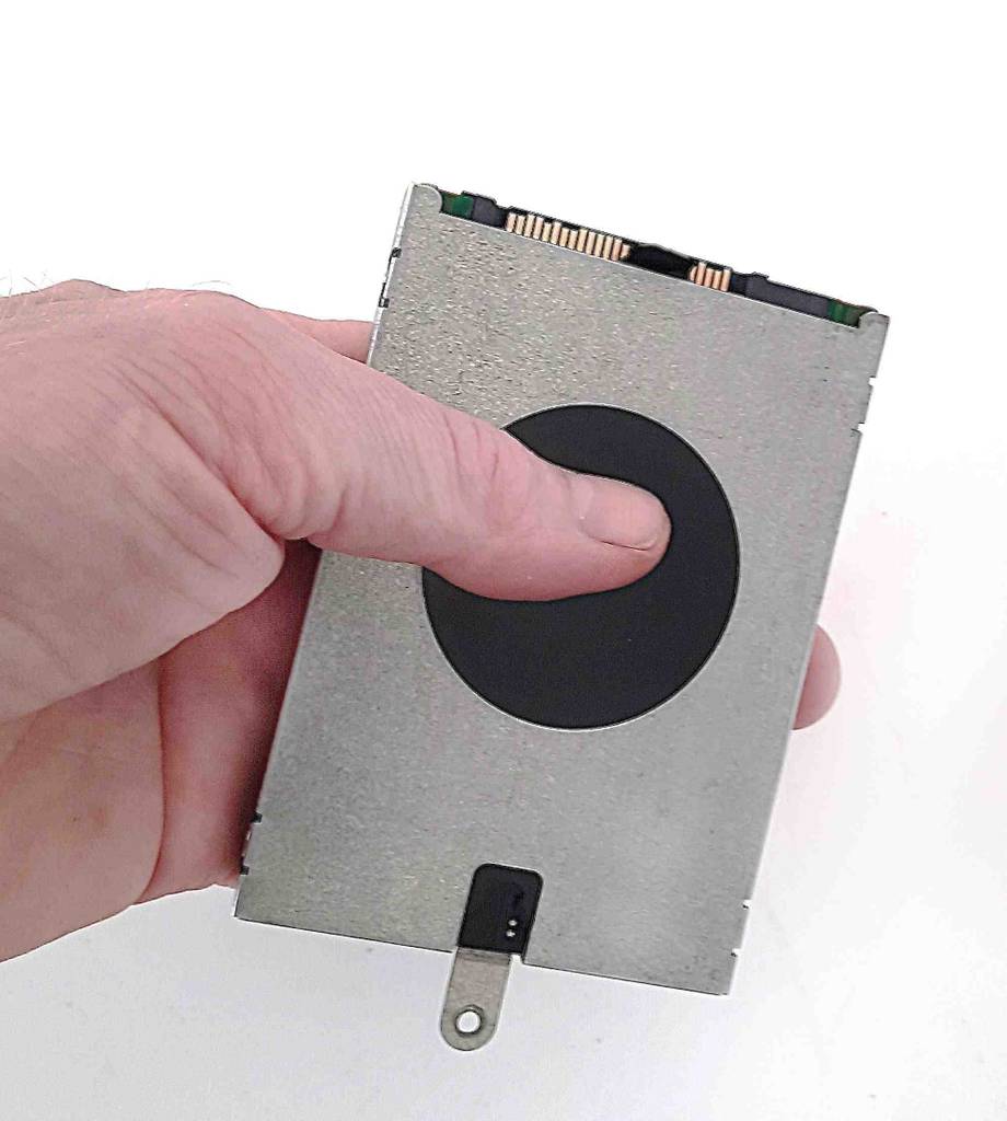 Im Test: Eine Hand hält eine 2,5-Zoll-Festplatte mit dem Daumen darauf vor einer weißen Wand.