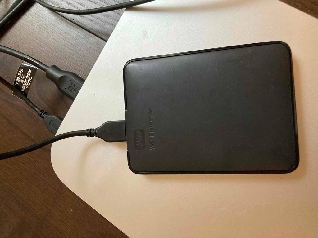 Schwarze Western-Elements-HDD-Festplatte liegt getestet und per Kabel verbunden auf einer hellen Computereinheit.