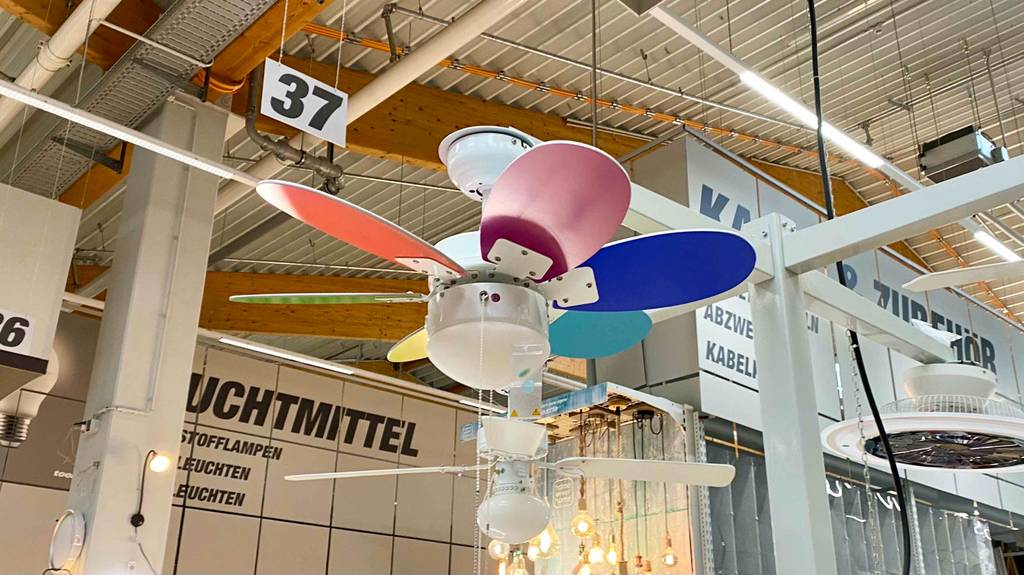 Mehrere Deckenventilator im Test inklusive Beleuchtung sind an der Decke in einem Verkaufsbereich für Leuchtmittel ausgestellt.