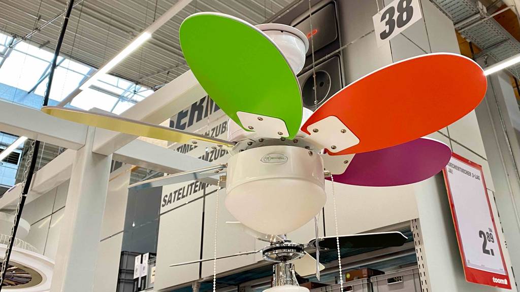 Ein bunter Deckenventilator im Test inklusive Beleuchtung ist an der Decke in einem Verkaufsbereich ausgestellt.