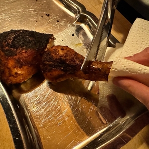 Eine Hand hält ein Stück Fleisch während dem Schneiden mit der Westmark-Geflügelschere fest