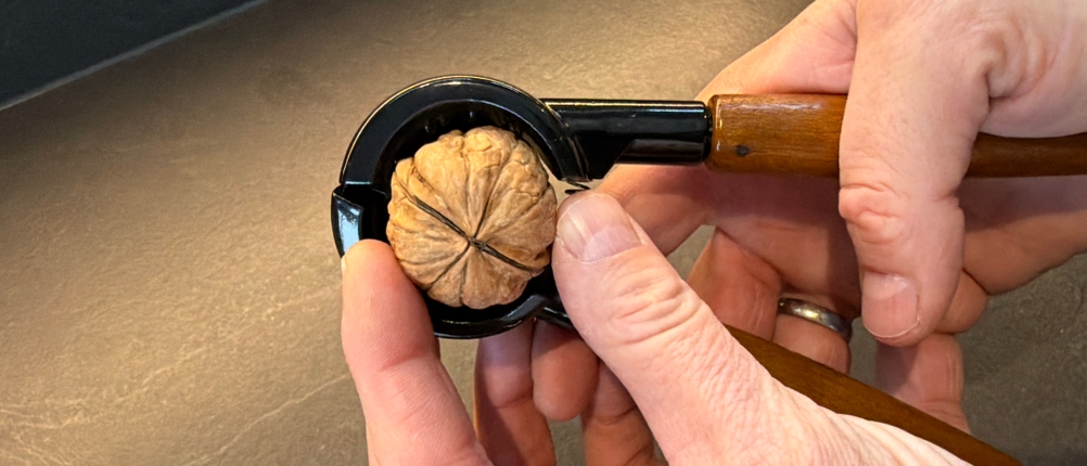 Eine Hand legt eine Walnuss in den Westmark-Nussknacker Sieger Nussprofi Deluxe