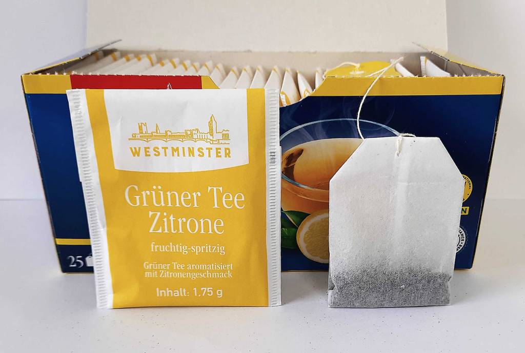 Im Test: grüner Tee im Beutel steht ausgepackt vor seiner Schachtel mit 25 Stück.