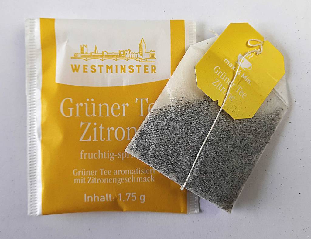 Im Test: Der grüne Tee-Beutel liegt ausgepackt oberhalb seines gelben Verpackungsbeutels auf einer weißen Oberfläche.