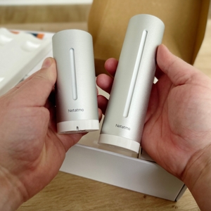 Außensensor und Basissation der Wetterstation von Netatmo werden nebeneinandergehalten.