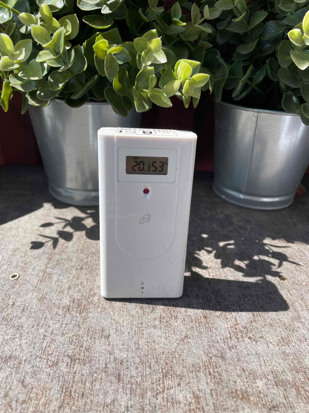 Das getestete Außenmessgerät einer Wetterstation steht draußen im Garten.