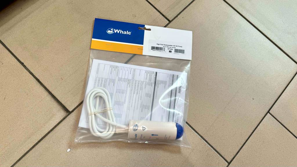 Eine Tauchpumpe 12v liegt verpackt zum Testen auf einem Fliesenboden.