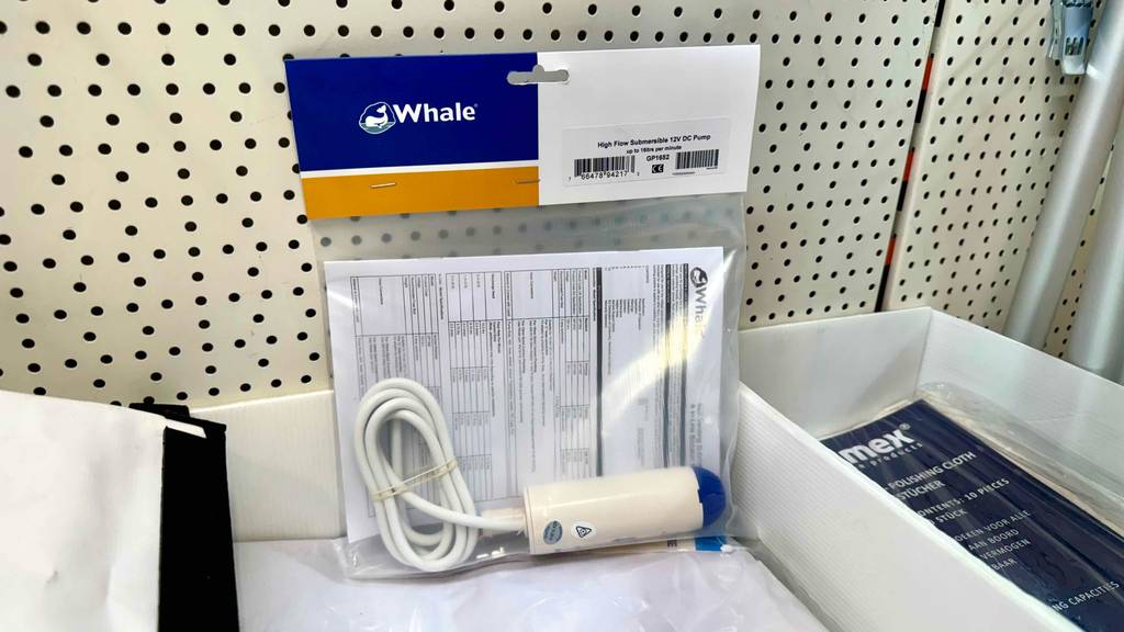 Im Test: Eine Tauchpumpe 12v hängt in durchsichtiger Originalverpackung einem Lochregal.