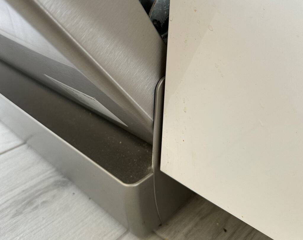 Detailansicht der vorderen Standflächenabdeckung bei geöffneter Vorderklappe eines frei stehenden Geschirrspülers im Test.