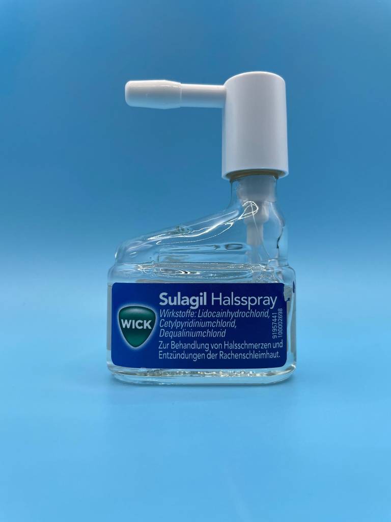 Im Test: ein Halsspray innerhalb eines Zerstäubers vor einem hellblauen Hintergrund.