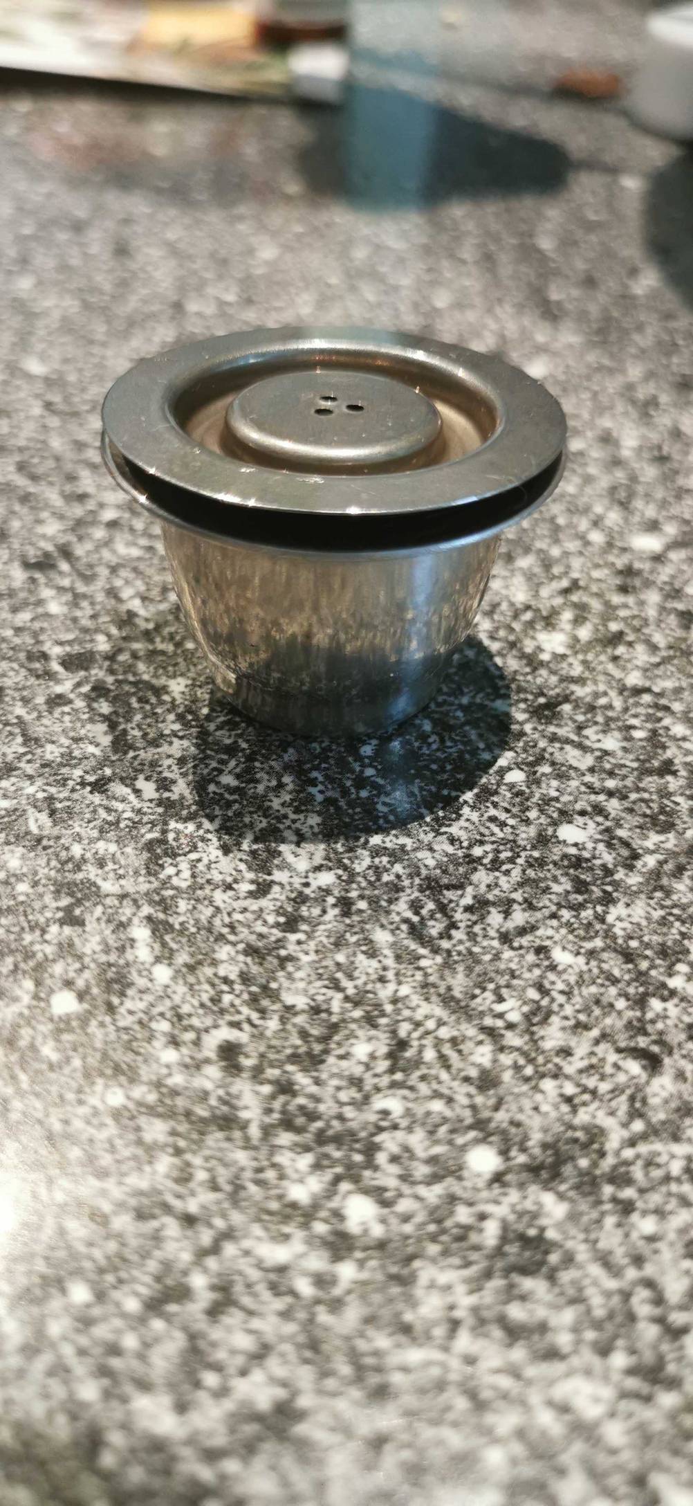 Wiederverwendbare Kaffeekapseln getestet: Eine Kapsel mit Deckel auf einer Arbeitsfläche.
