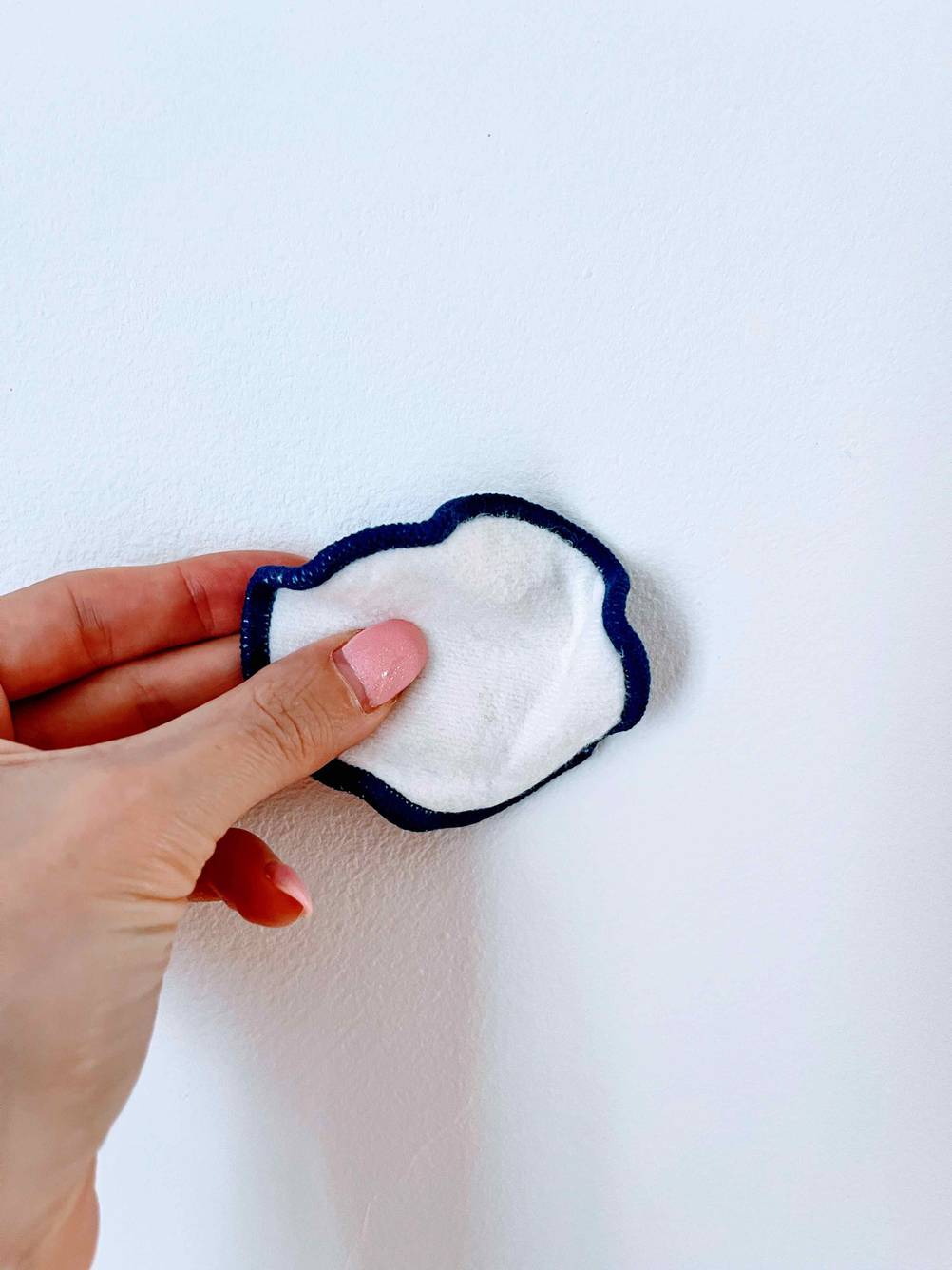 Wiederverwendbare Wattepads getestet: Eine Hand hält ein Pad vor eine helle Wand.