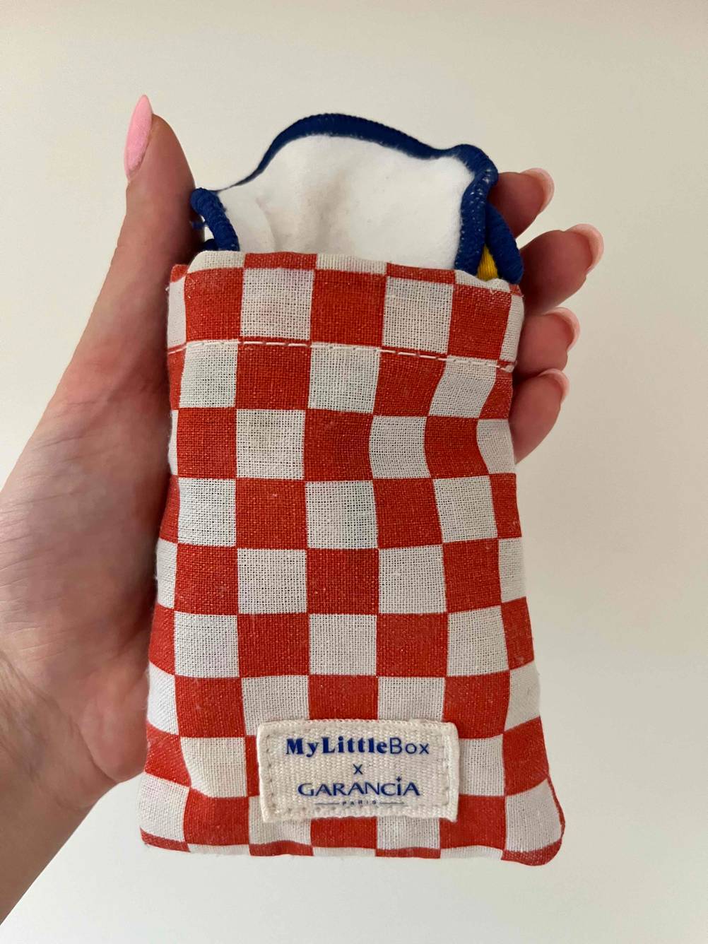 Eine Hand hält ein Säckchen mit den getesteten wiederverwendbaren Wattepads vor eine helle Fläche.