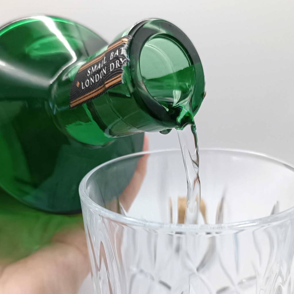 Detailansicht einer Grünglasflasche mit London-Dry-Gin im Test, aus der transparente Flüssigkeit in ein Glas fließt.