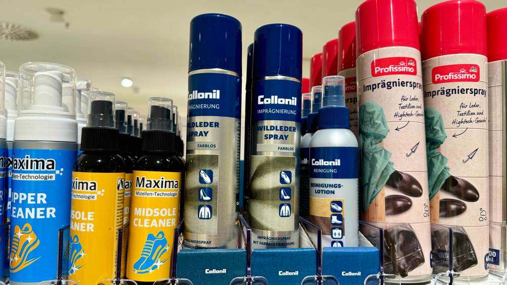 Mehrere Wildledersprays im Test in einem Verkaufsregal neben anderen Produkten.