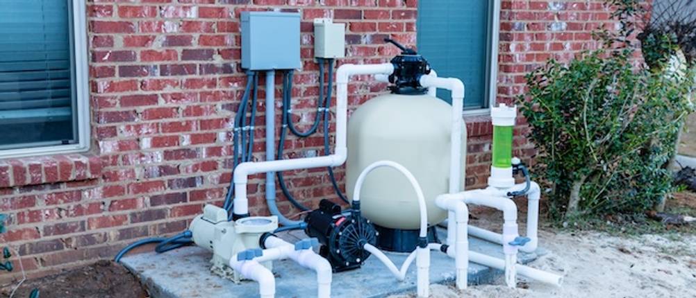 WilTec-Poolpumpen-Test: Eine Filteranlage mit Poolpumpe vor einer Hauswand.
