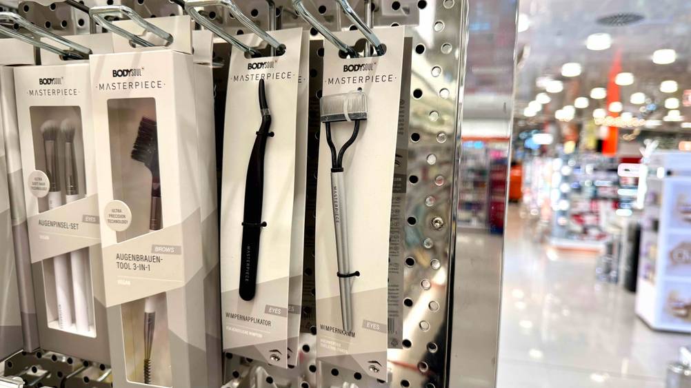 Ein Wimpernkamm im Test hängt neben anderen Produkten in einem Regal.
