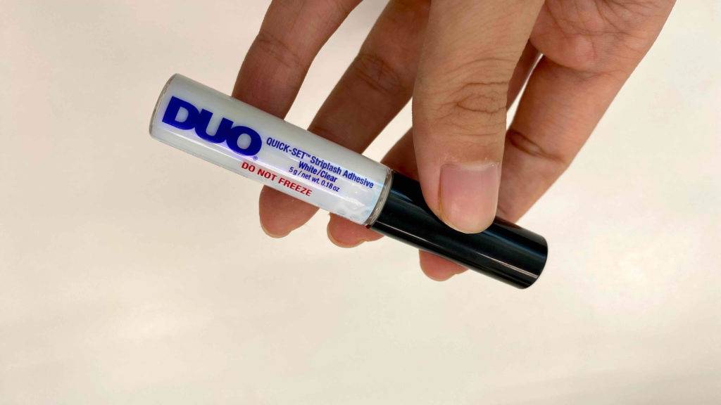 DUO-Wimpernkleber in der Hand. 