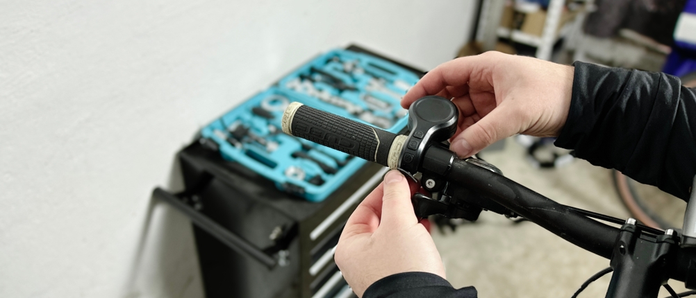 Eine Person montiert die Wind&Moon-Fahrradklingel an den Lenker eines Fahrrads. Im Hintergrund ist eine Werkzeugbox zu sehen.