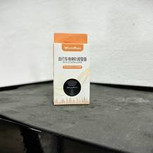 Die Wind&Moon Fahrradklingel in der Originalverpackung auf einem Tisch vor einer weißen Wand.