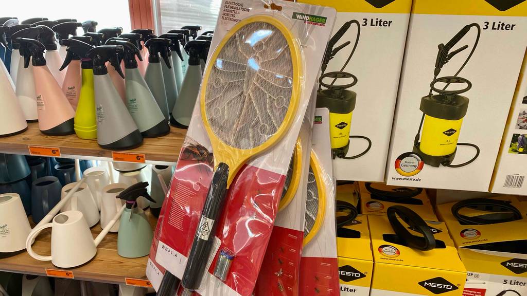 Im Test: eine elektrische Fliegenklappe hängt eingeschweißt in einer weiß-roten Verpackung am Verkaufsregal vor Garten-Utensilien.