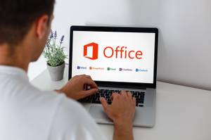 Ein Mann an einem Laptop mit Office-Paket sitzend.