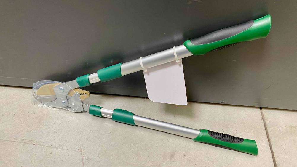 Teleskop-Heckenschere getestet: Eine Schere lehnt an einer Metallwand auf einem hellen Boden.
