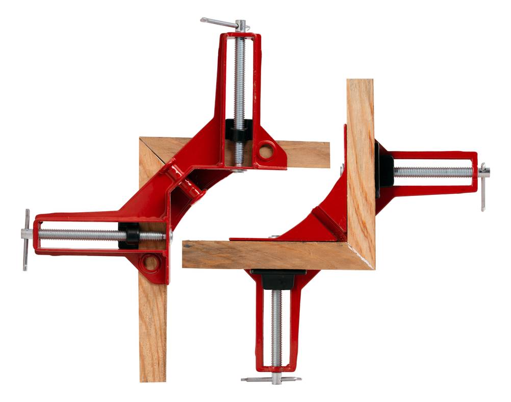 Winkelspanner im Test: Zwei rot lackierte 90-Grad-Winkelspanner mit Spindeln, die zwei Eckverleimungen von Latten fixieren.