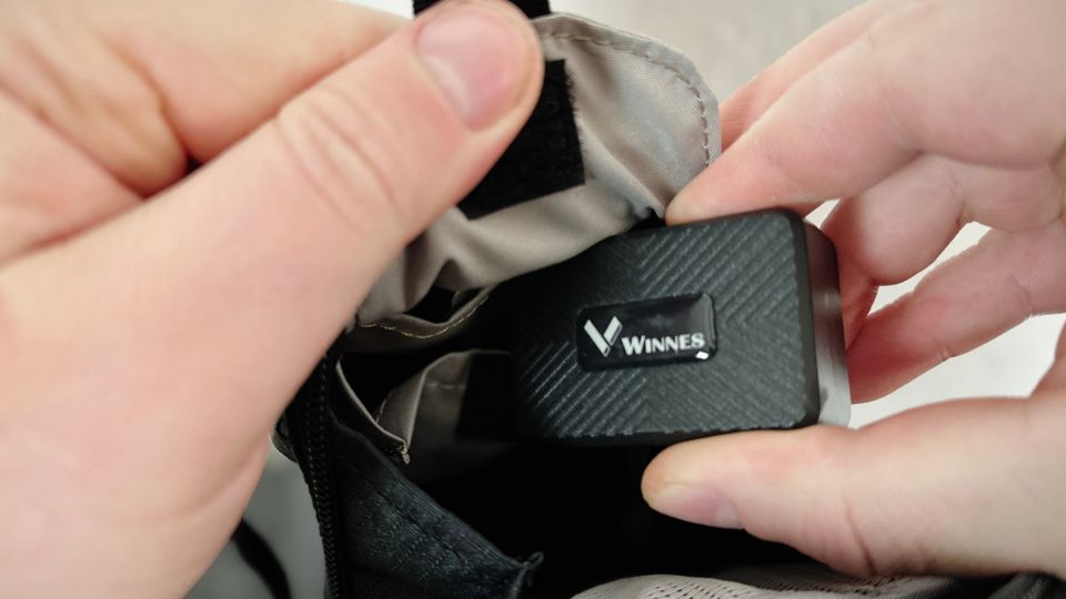 Ein Winnes TK913 GPS Tracker wird in eine geöffnete Fahrradsatteltasche gelegt. Zwei Hände halten Tracker und Tasche fest.