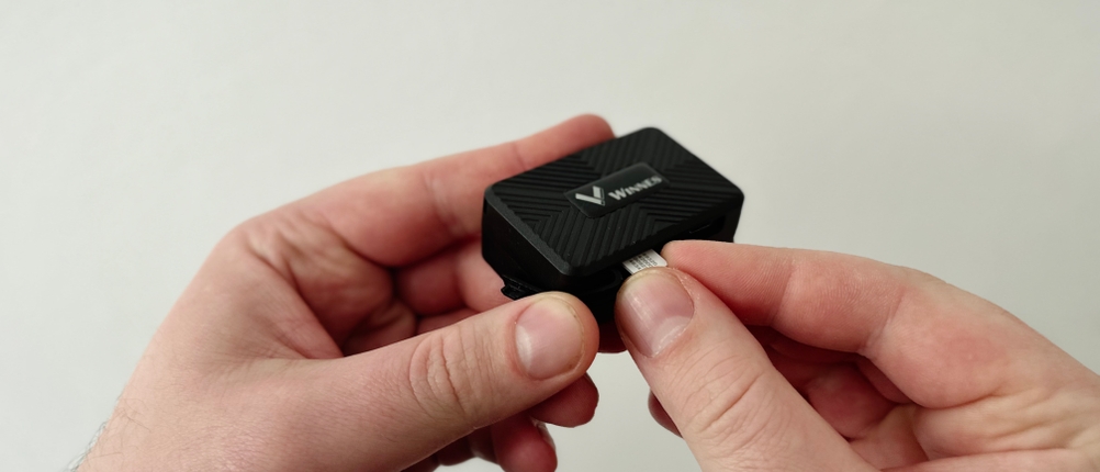 Eine SIM-Karte wird in den Kartenschlitz des Winnes TK913 eingesetzt. Das Gerät wird mit zwei Händen gehalten.