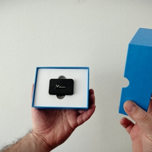 Zwei Hände öffnen die Verpackung des Winnes TK913 GPS Trackers. Das Gerät liegt mittig in einer Aussparung.