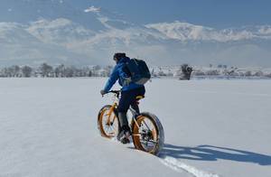 Radfahren im Schnee mit Bergen im Hintergrund