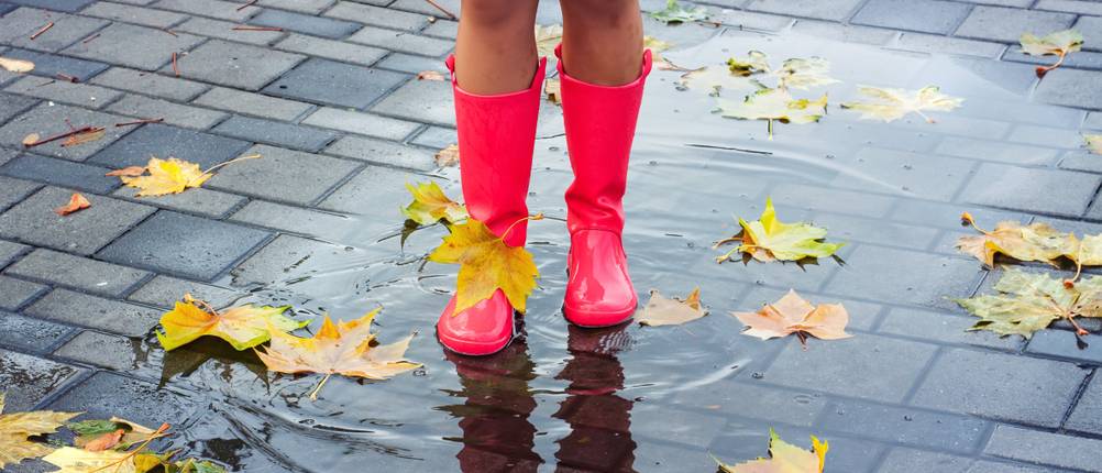 Winter-Gummistiefel im Test: Eine Frau mit roten Gummistiefeln in einer Pfütze.