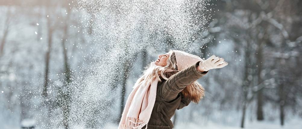 Winterjacke für Damen im Test: Eine Frau jubelt im Schnee.