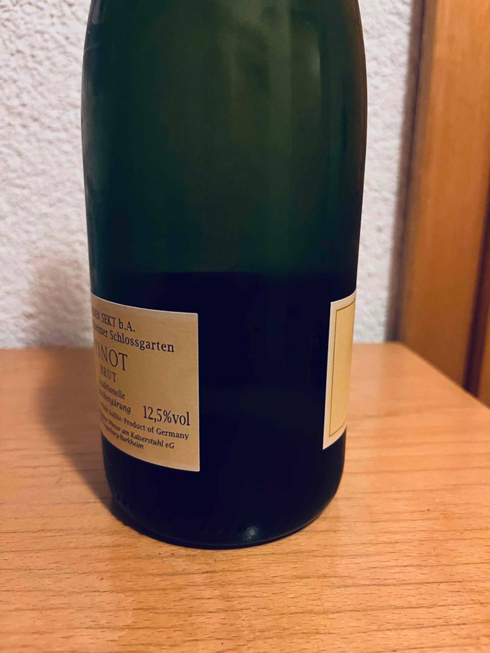 Winzersekt getestet: Seitenansicht einer Flasche auf einem Holztisch.