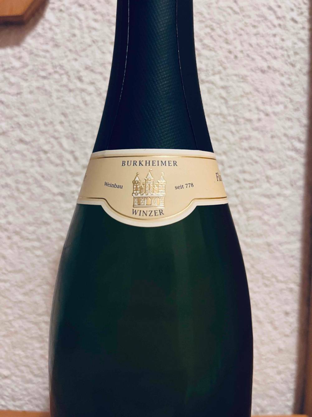 Nahaufnahme der Banderole einer Flasche des getesteten Winzersekts vor einer hellen Wand.