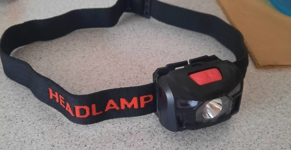 Stirnlampe im Test: ein schwarzes Modell liegt auf einer grauen Fläche.