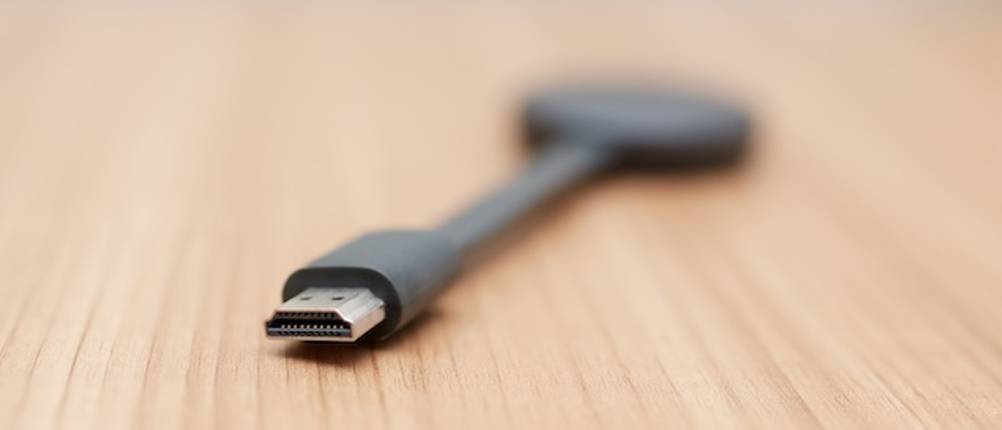 Wireless-HDMI-Test: Ein Wireless-HDMI liegt auf einer Holzoberfläche mit dem Anschluss nach vorne gerichtet.