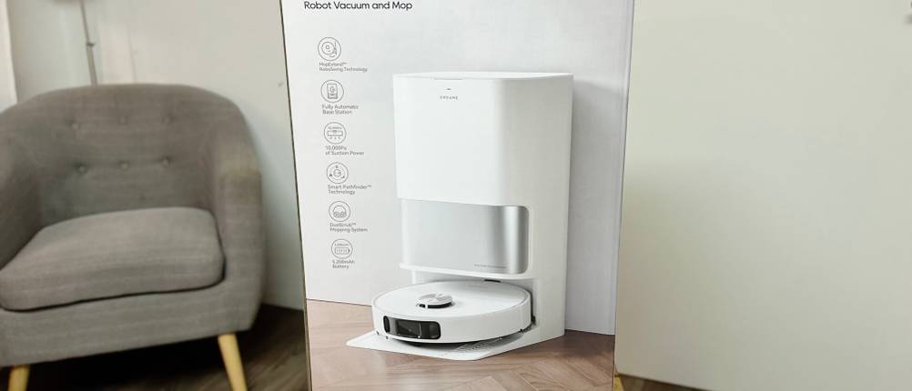 Die Verpackung des Dreame-Wischroboters steht auf einem Holzhocker.