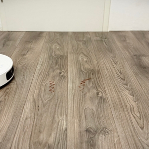 Der Wischroboter von Dreame entfernt Ketchup-Flecken von einem grauen Laminatboden.