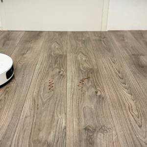 Der Wischroboter von Dreame entfernt Ketchup-Flecken von einem grauen Laminatboden.