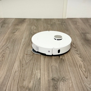 Der Wischroboter von Dreame entfernt Ketchup-Flecken von einem grauen Laminatboden.