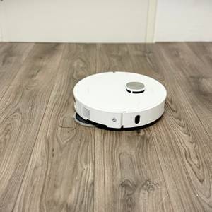 Der Wischroboter von Dreame entfernt Ketchup-Flecken von einem grauen Laminatboden.