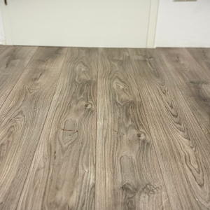 Der Wischroboter von Dreame entfernt Ketchup-Flecken von einem grauen Laminatboden.