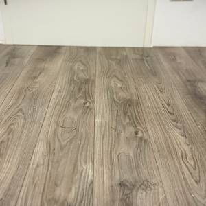 Der Wischroboter von Dreame entfernt Ketchup-Flecken von einem grauen Laminatboden.