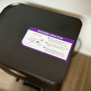 Ein Aufkleber mit Hinweisen zur Positionierung der Basisstation ist auf ebendieser des Monsga-Wischroboters angebracht.