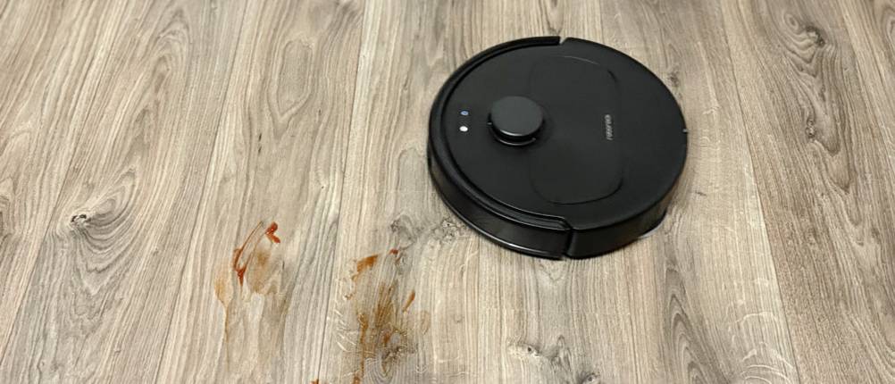 Der Wischroboter von Roborock wischt Ketchup von einem grauen Laminatboden auf.